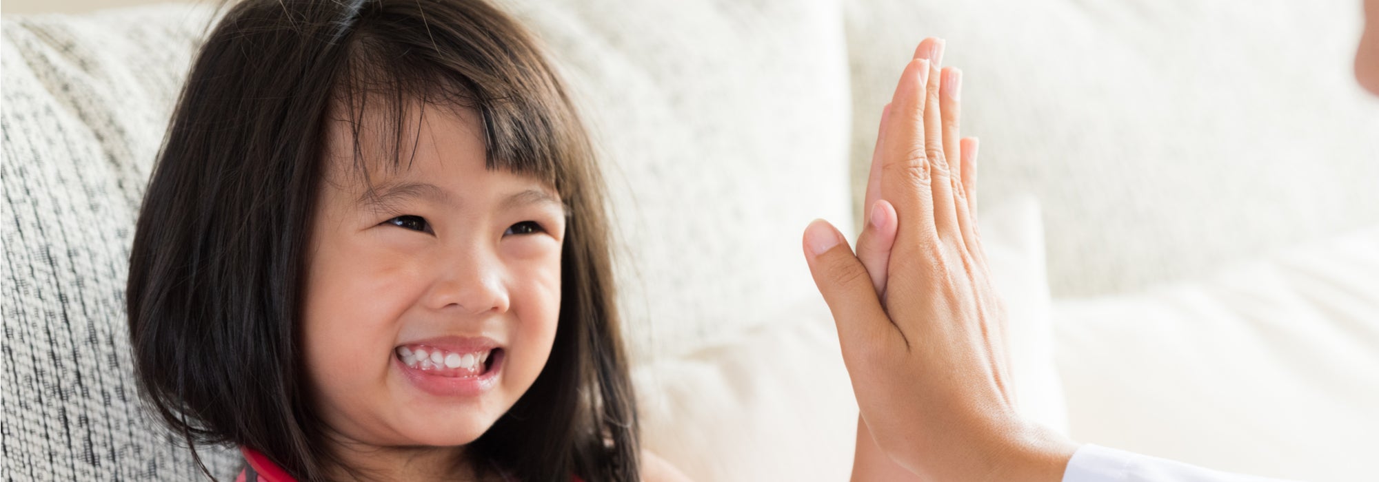 Cute young girl smiling while giving a high five to the pediatric dentist.