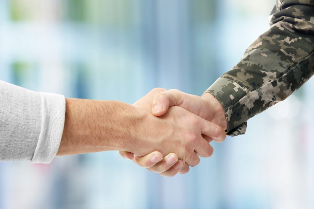 Close up of a civilian and soldier shaking hands. 