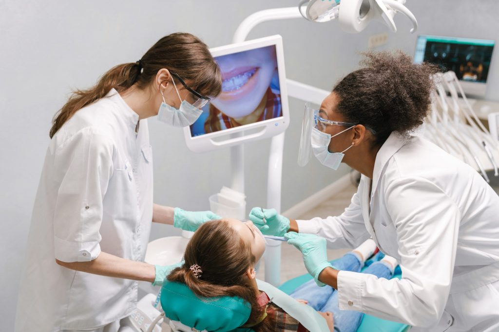  Dentists that take Medicaid look at image on screen of mouth of young girl in dental chair while providing dental services. 