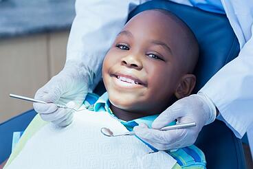 Close up view of little african american boy patient having dental treatment at dentist's office.