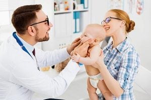 A male dentist looking at the baby's teeth.