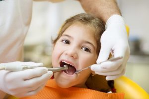 Little girl at a pediatric dentist with mask and gloves service child tooth care in a dental dentistry clinic.