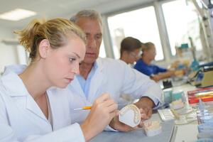 Two dentists checking on a dentures.