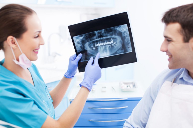 Female dentist explaining dental Xray to male patient in clinic