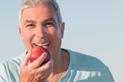 Portrait of a mature man about to eat a red apple.