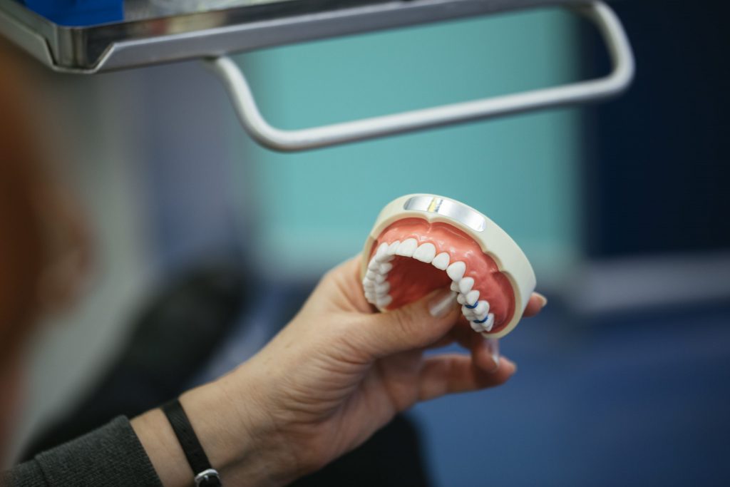 A woman holds a set of dentures during a fitting appointment with a Philadelphia prosthodontist. 