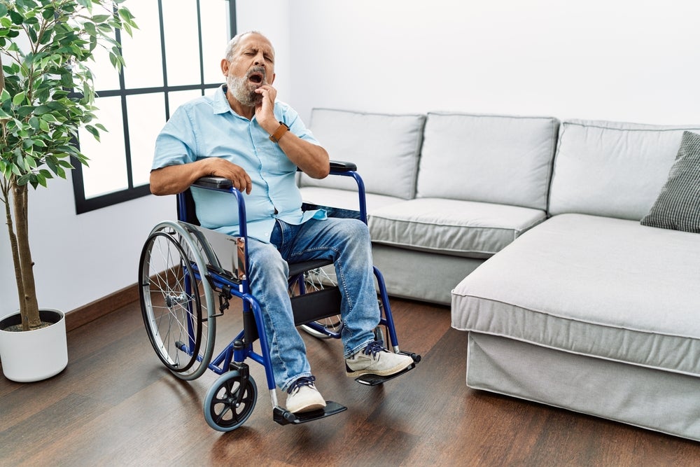 A man in a wheelchair holds his mouth in pain because he needs to see a dentist. 