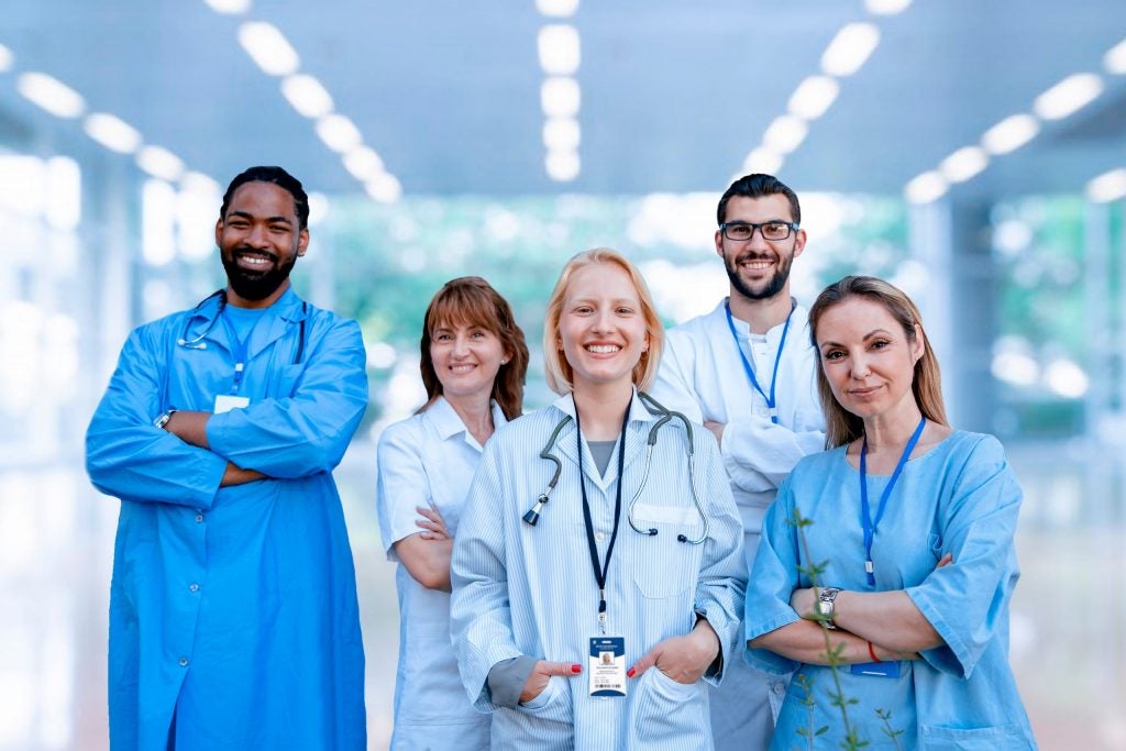 Five medical professionals on a cancer care team, including a dentist for cancer patients, pose in the hospital hallway.