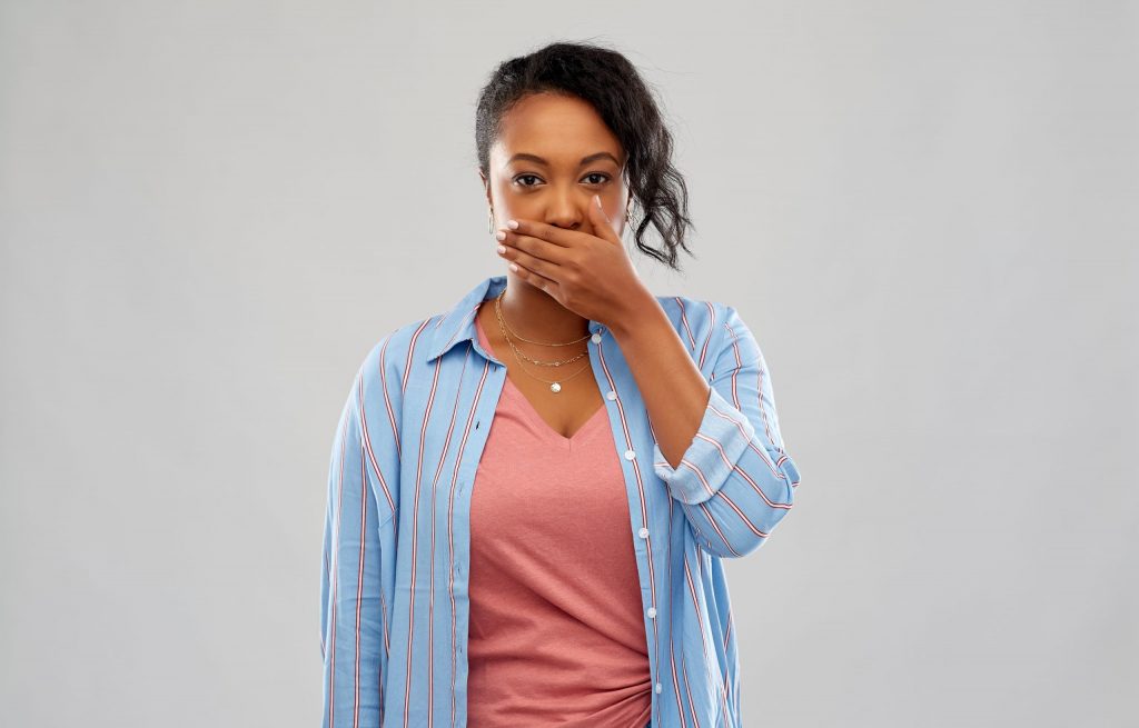  A young woman holds her hand to her mouth, wondering how to get rid of bad breath.