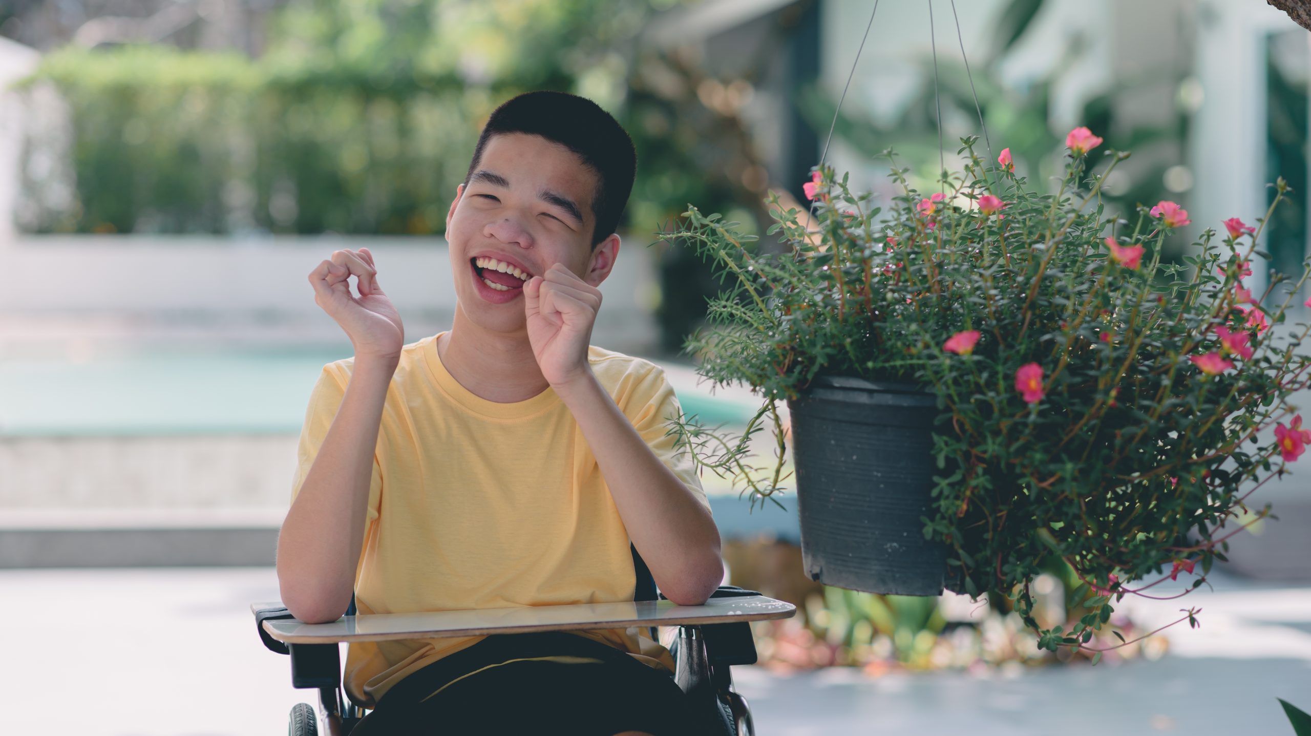  Teenage boy with cerebral palsy smiles in his wheelchair, outside after a visit to a special needs pediatric dentist.