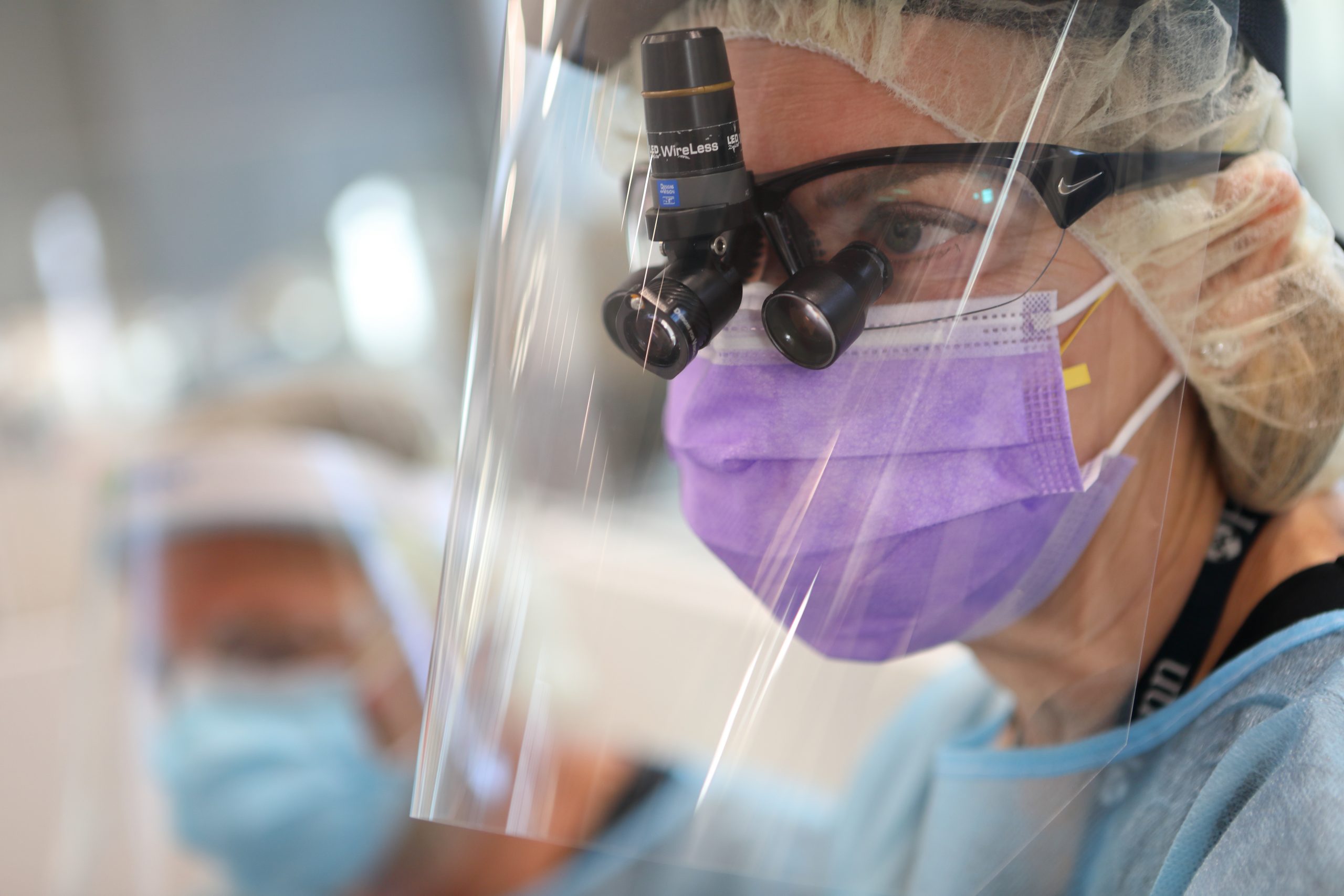 A Penn Dental Medicine dentist wears a protective mask and face shield as she looks at oral cancer screening information. 