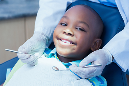 A young boy smiles while at the dentist having his teeth examined. 