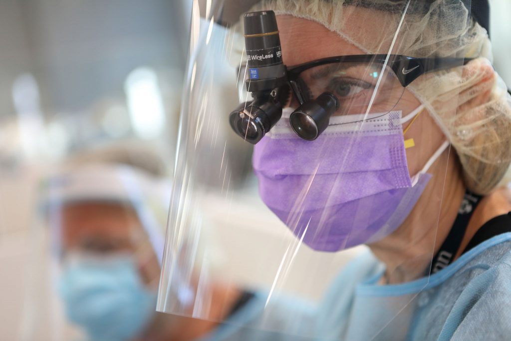 A Penn Dental Medicine dentist wearing a face shield and mask gets ready to see a patient.