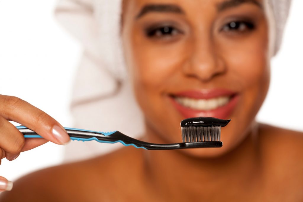 A woman holds a toothbrush with charcoal toothpaste, but does charcoal toothpaste work? 