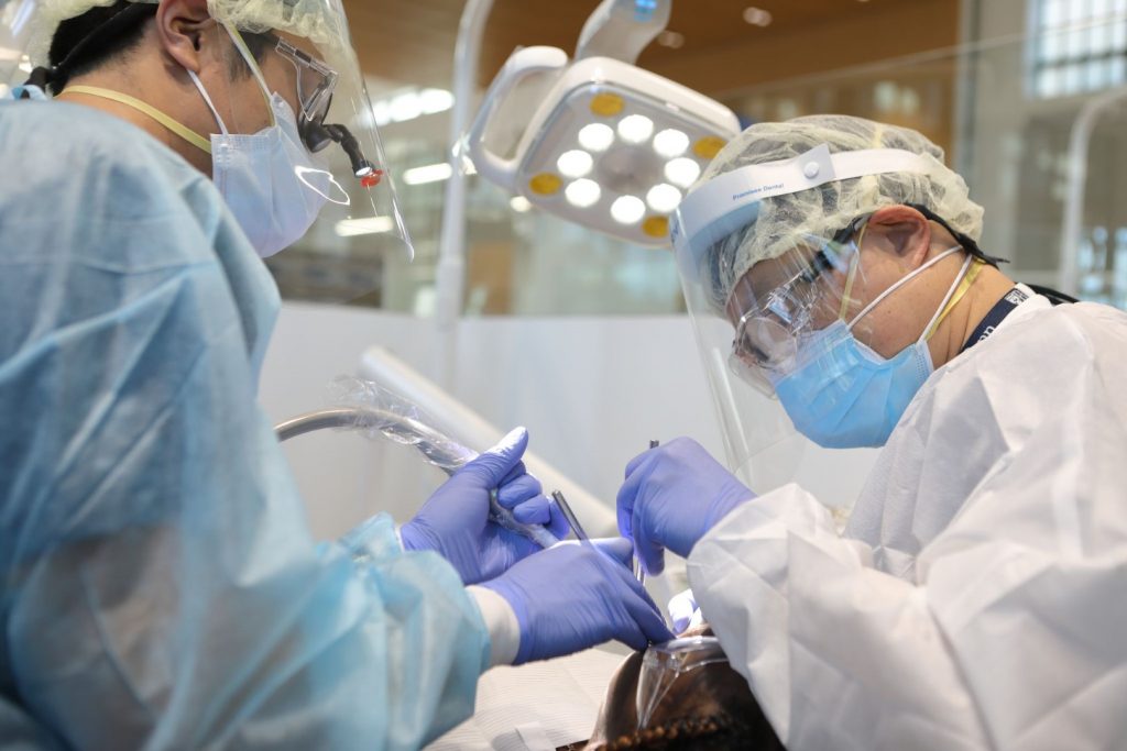 Two PDM periodontist specialists work on a patient who is suffering from periodontal disease.