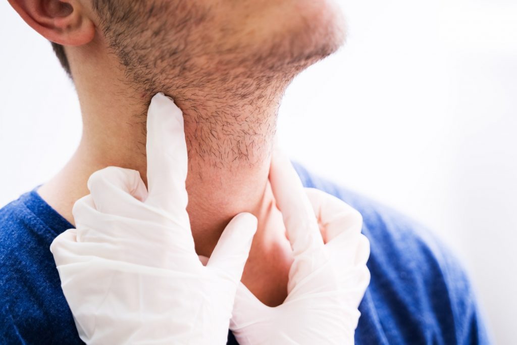 A gloved dentist examines the neck of a patient suffering from salivary gland disorder. 