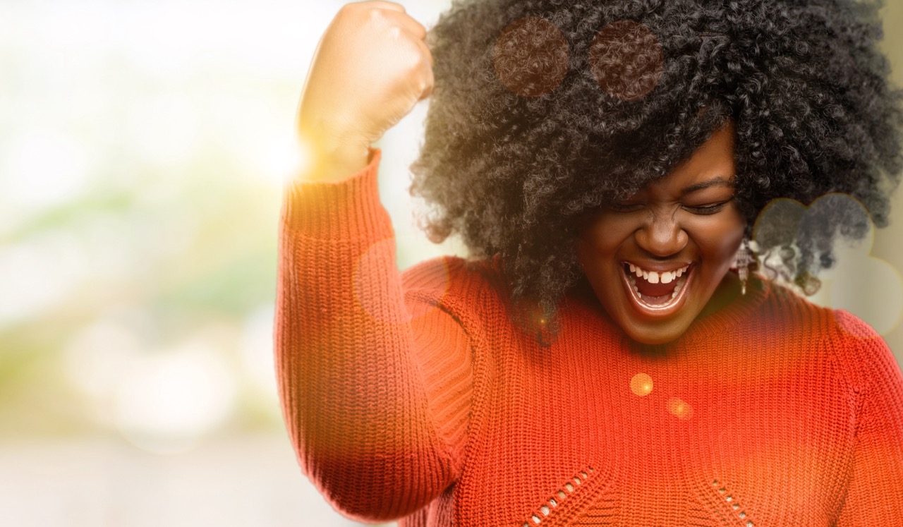 A young woman expresses a winning gesture now that her oral health and overall health are in control. 