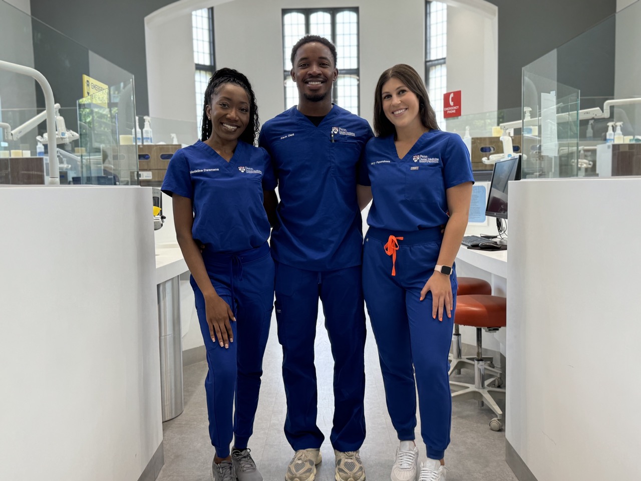 Madeline, Kevin, and Mary, three student dentists at Penn Dental Medicine, pose in scrubs for selfie.