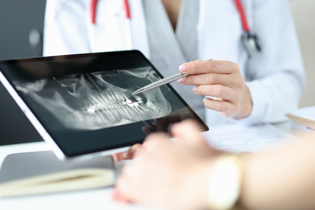 A dentist showing a patient an X-ray on a tablet. 