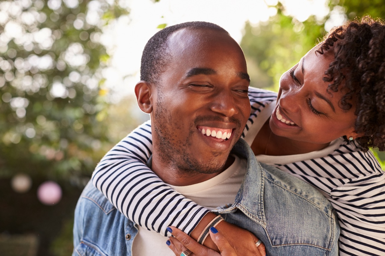 A young couple smiles while standing outside.