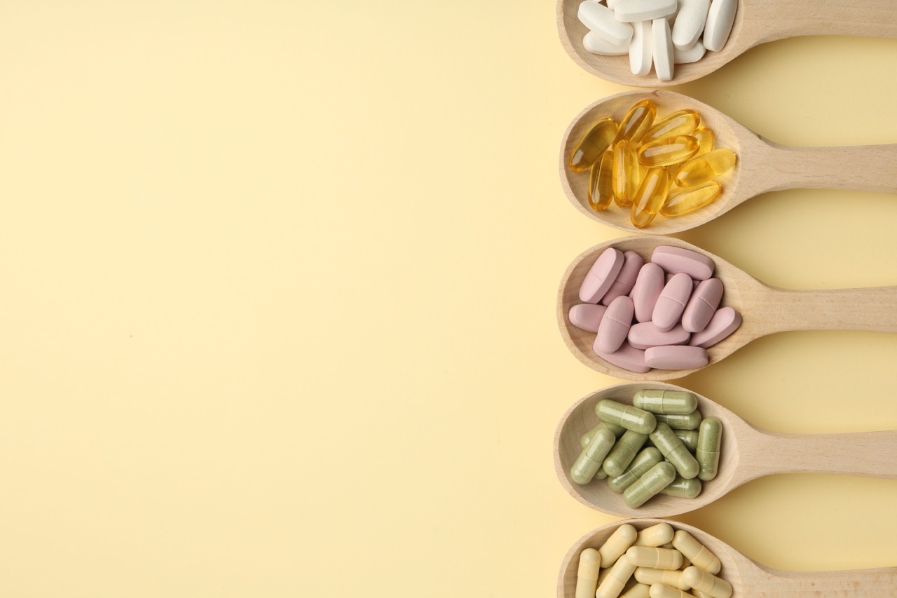 A row of wooden spoons with different colored vitamins for strong teeth on them is stacked vertically.