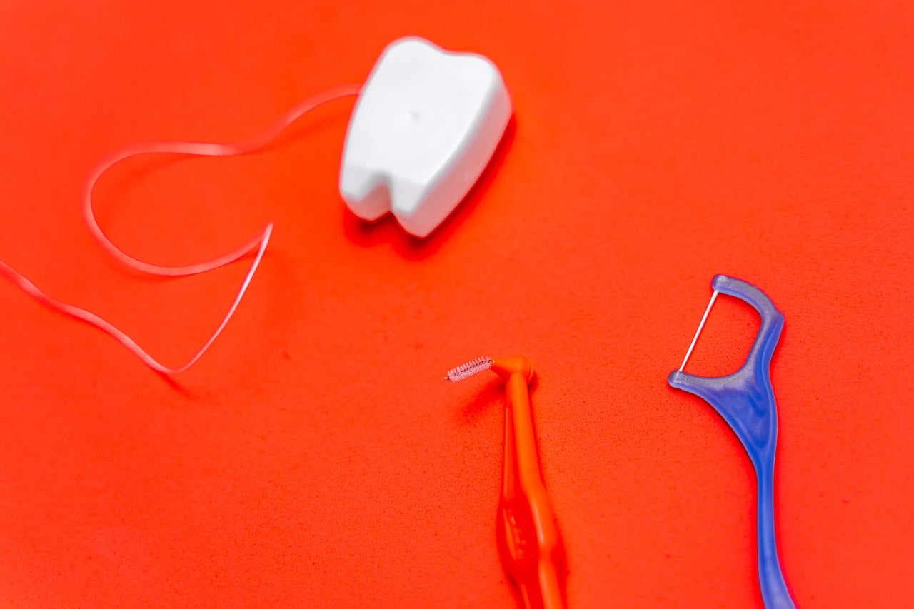 A display of different types of dental floss and flossers against a red background.