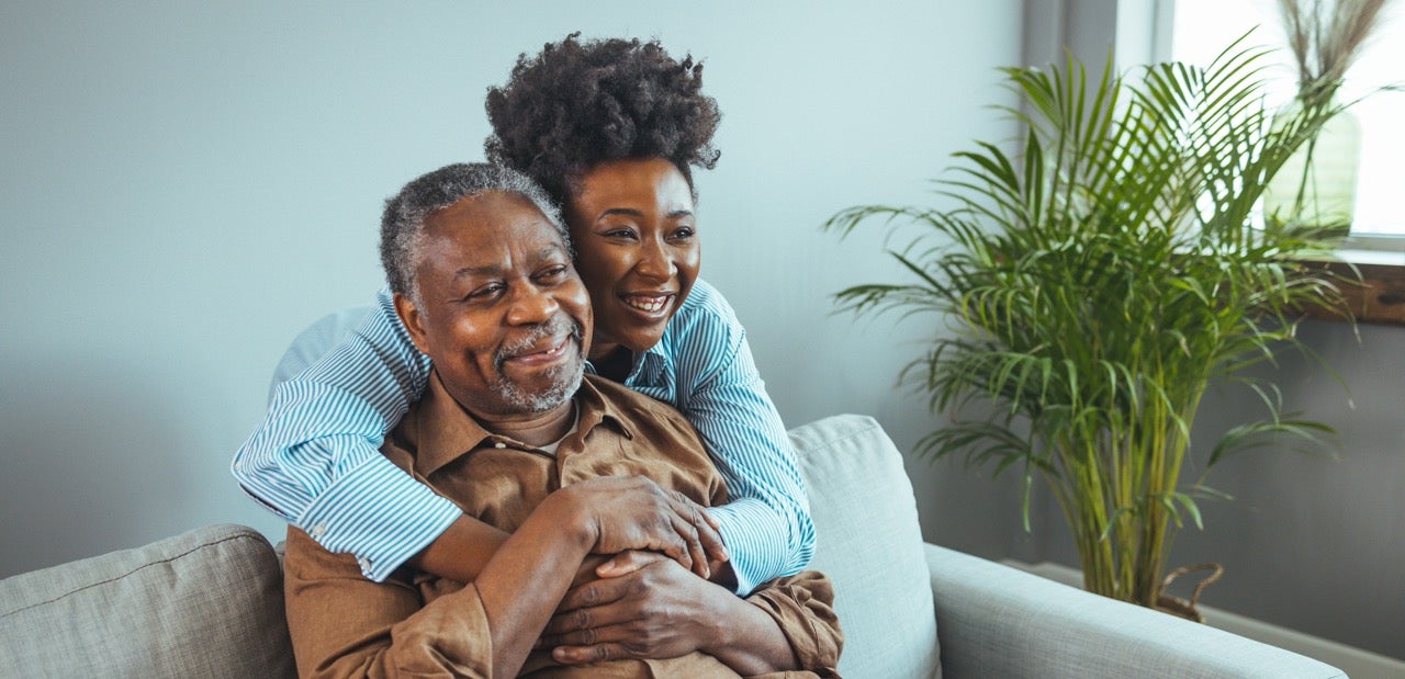 A woman hugs her father around the shoulders now that he’s recovered from oropharyngeal cancer. 