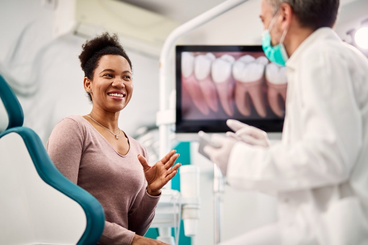 A young woman talks to the dentist about her wisdom teeth. 