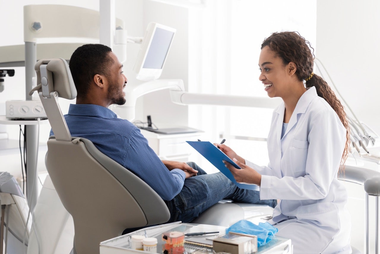 A man talks to his dentist in the dental exam room. 