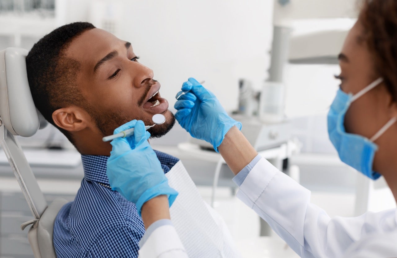 A young man undergoing dental treatment from a hygienist. 