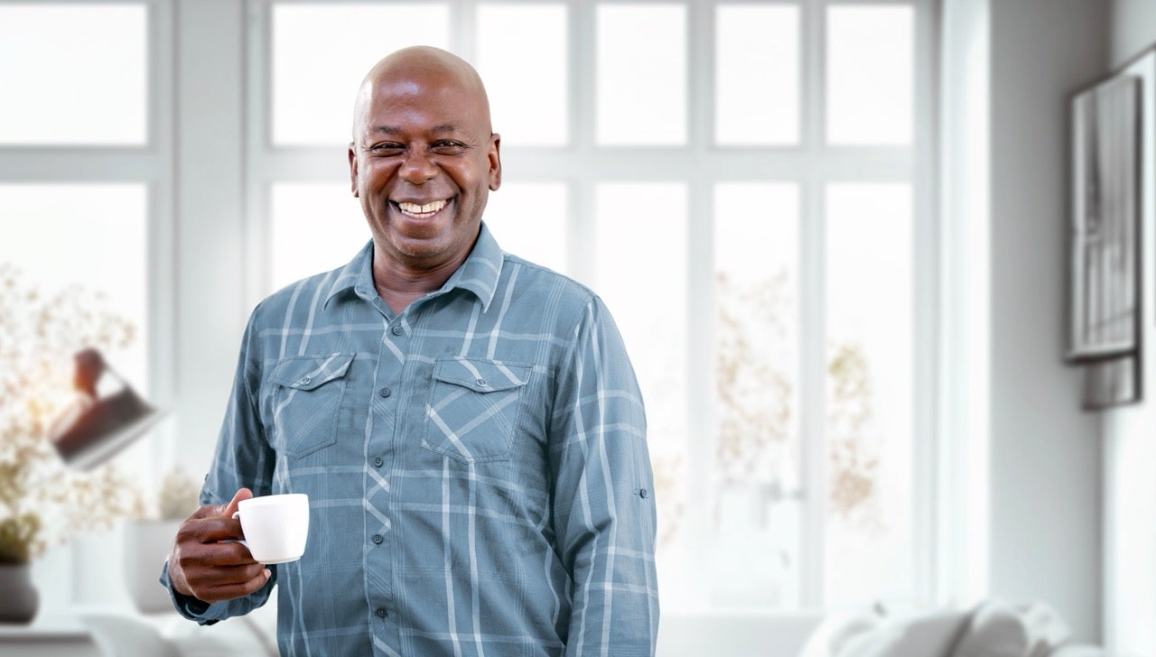 A happy middle-aged man smiles as he holds a cup of coffee.