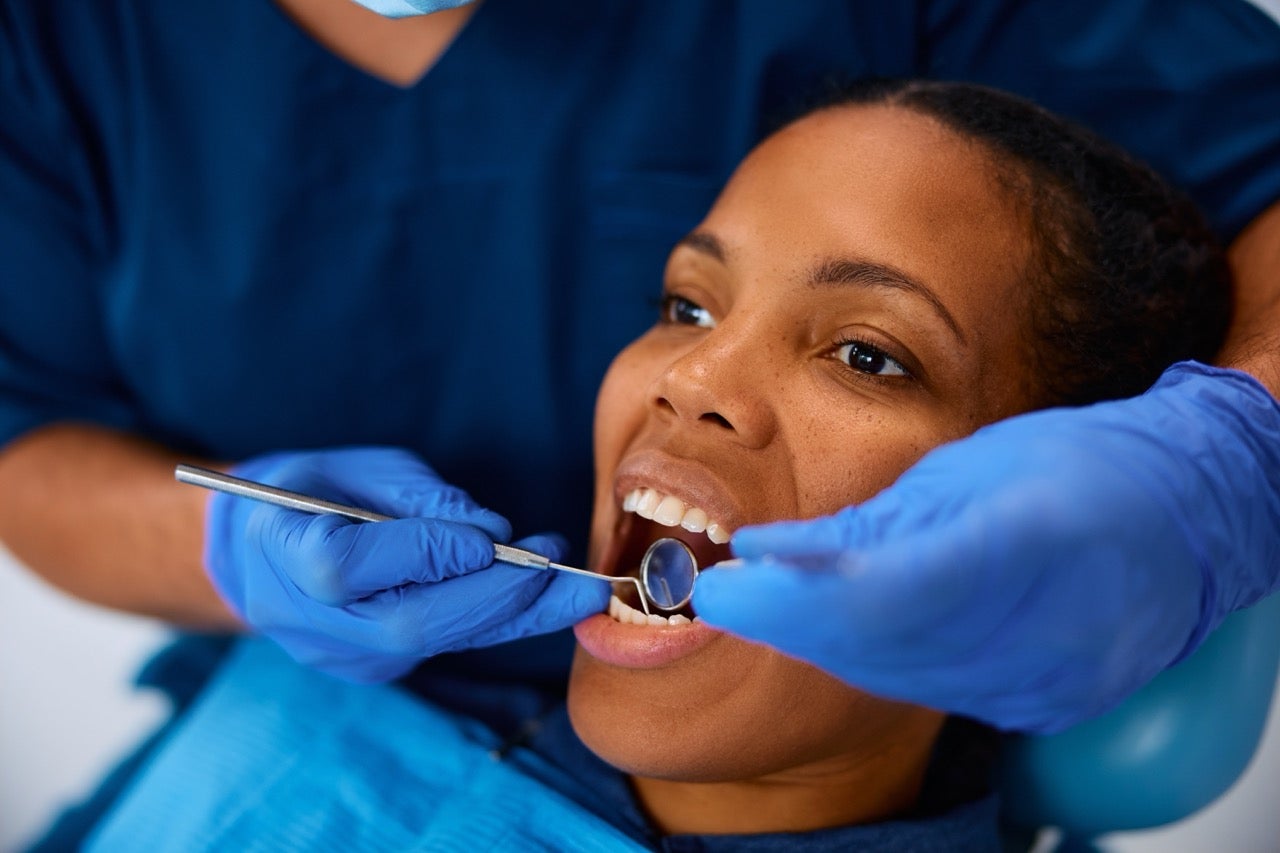 A dental hygienist examines a young woman’s teeth. 
