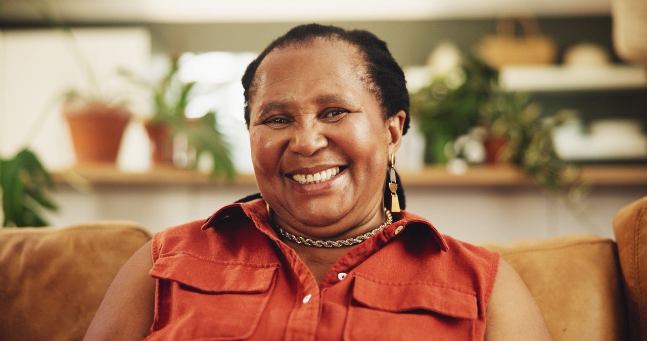 A happy woman wearing an orange blouse smiles because she no longer has gum health issues. 