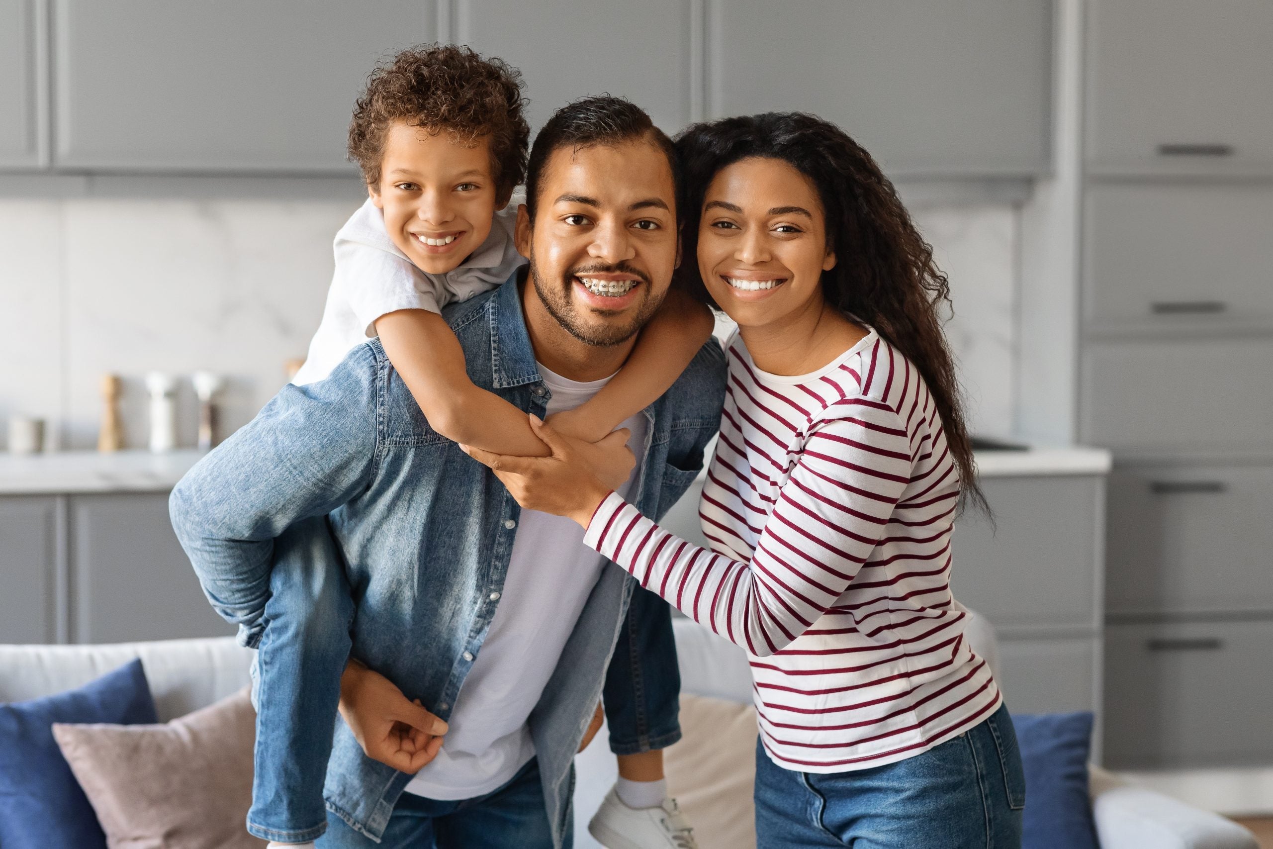 A dad holds his son on his back while his wife stands next to him. 