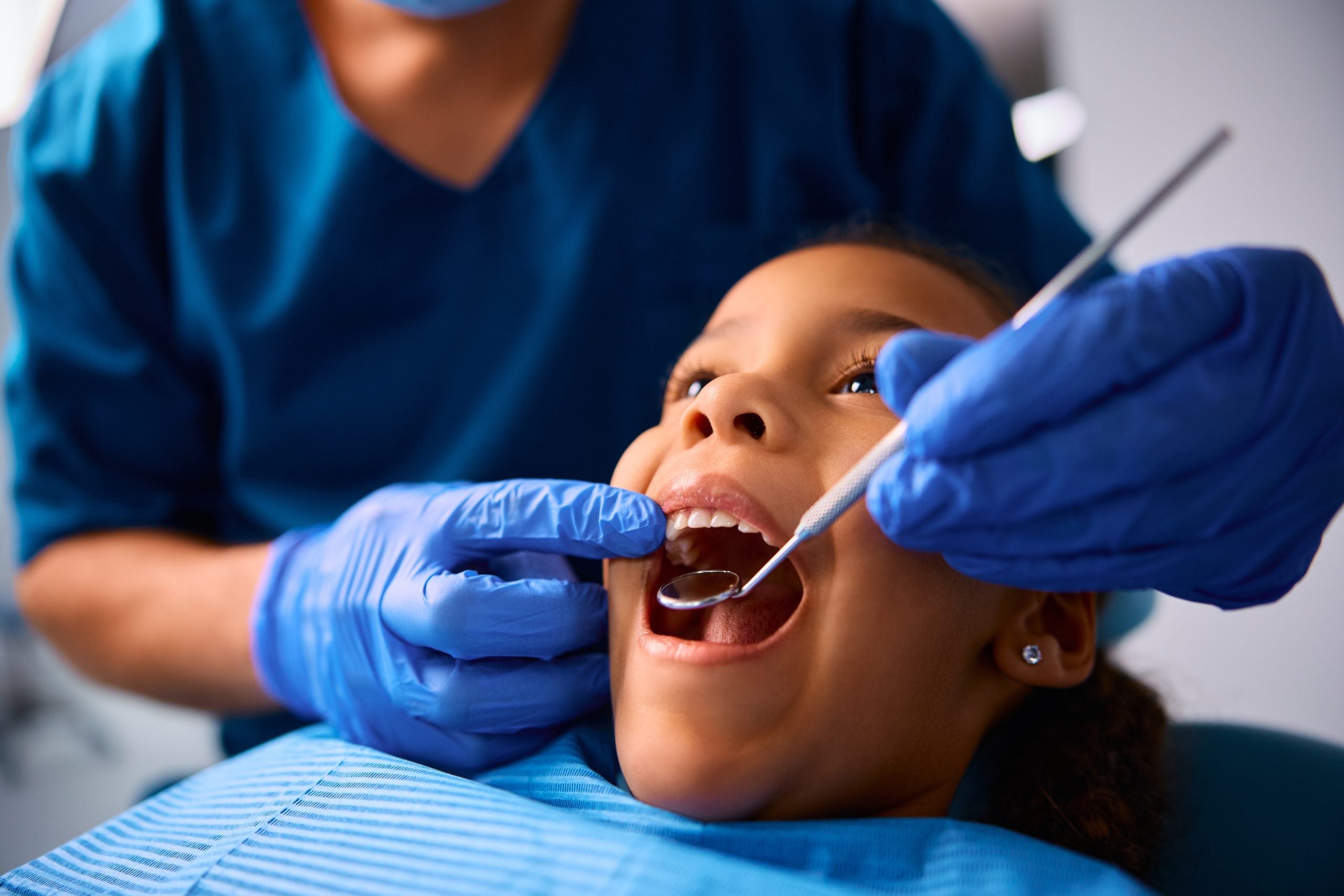 A dental hygienist examines a child’s teeth. 