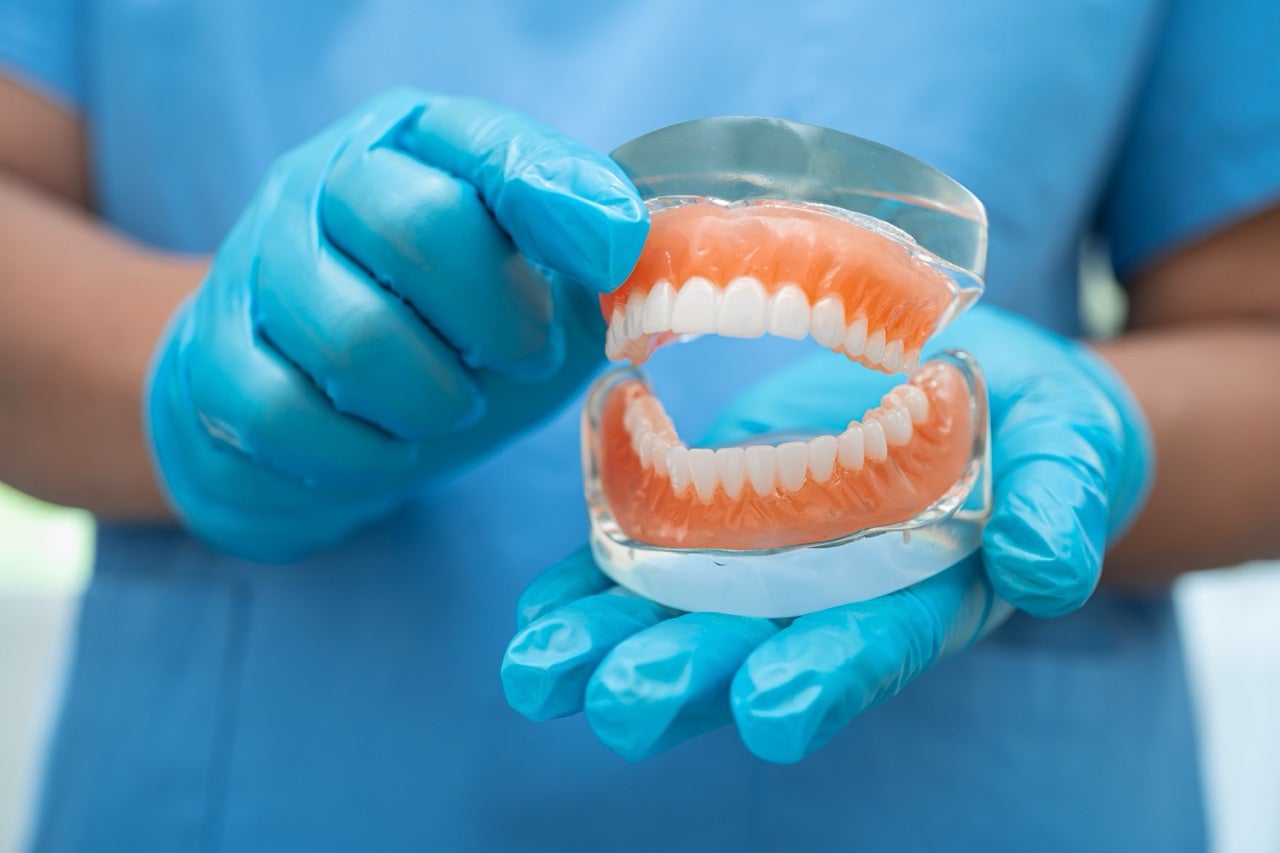 A dentist holds a model of upper and lower dentures.