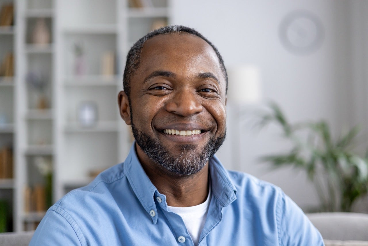 A smiling middle-aged man wearing a blue button-down shirt.
