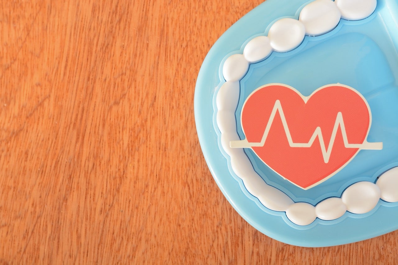 A red heart signifying good health on a blue plate teeth model represents the connection to oral health. 