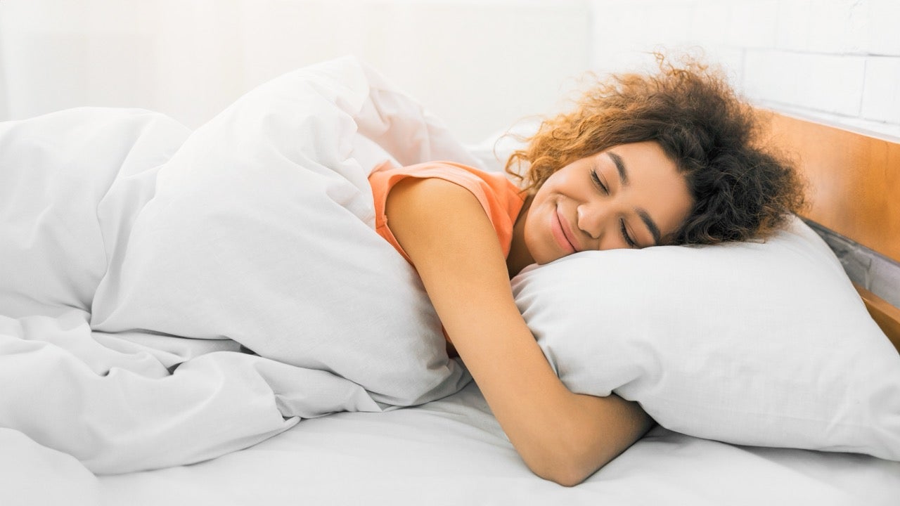A woman smiles as she wraps her arms around her pillow. 